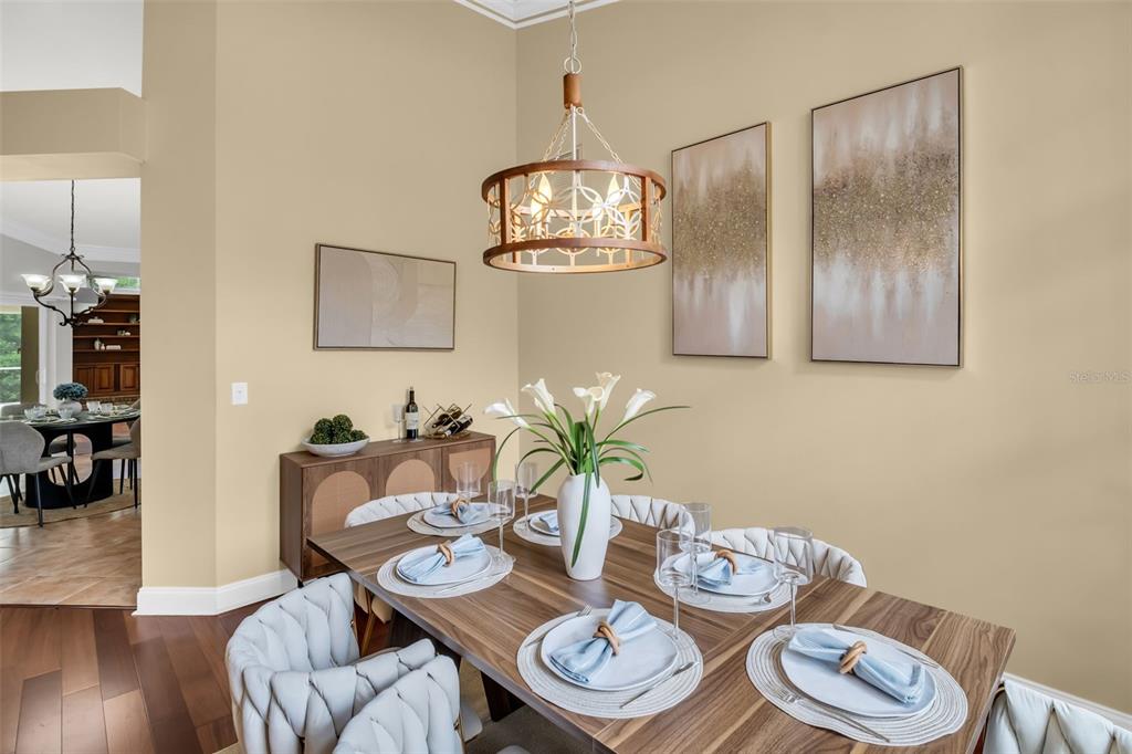 A dining room features a wooden table, upholstered chairs, a chandelier, and wall art — 1404 EAST LAKE WOODLANDS PARKWAY, OLDSMAR, FL