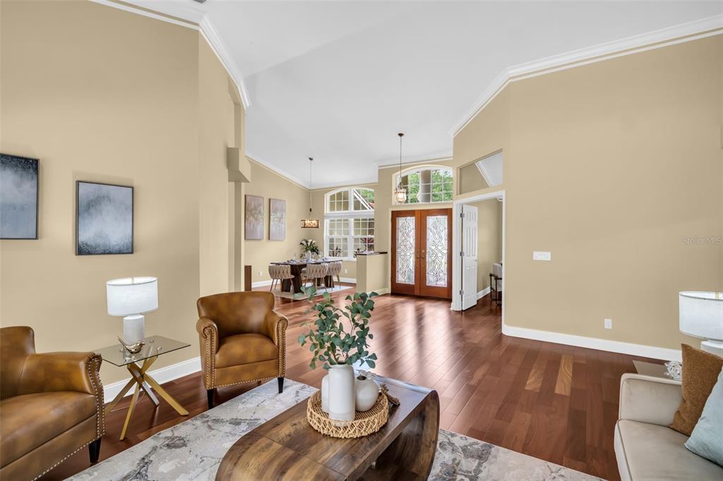 A living room with hardwood floors, tan walls, and a view into the dining area — 1404 EAST LAKE WOODLANDS PARKWAY, OLDSMAR, FL