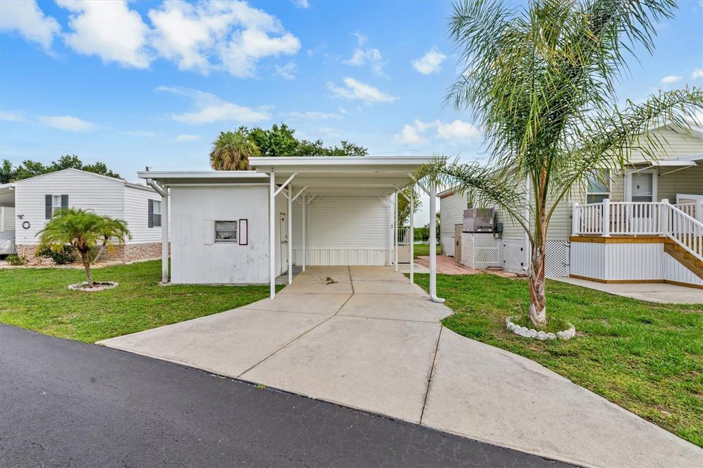 A white mobile home features a concrete driveway and an attached metal carport — 8320 RIVERSIDE DRIVE UNIT 99, PUNTA GORDA, FL