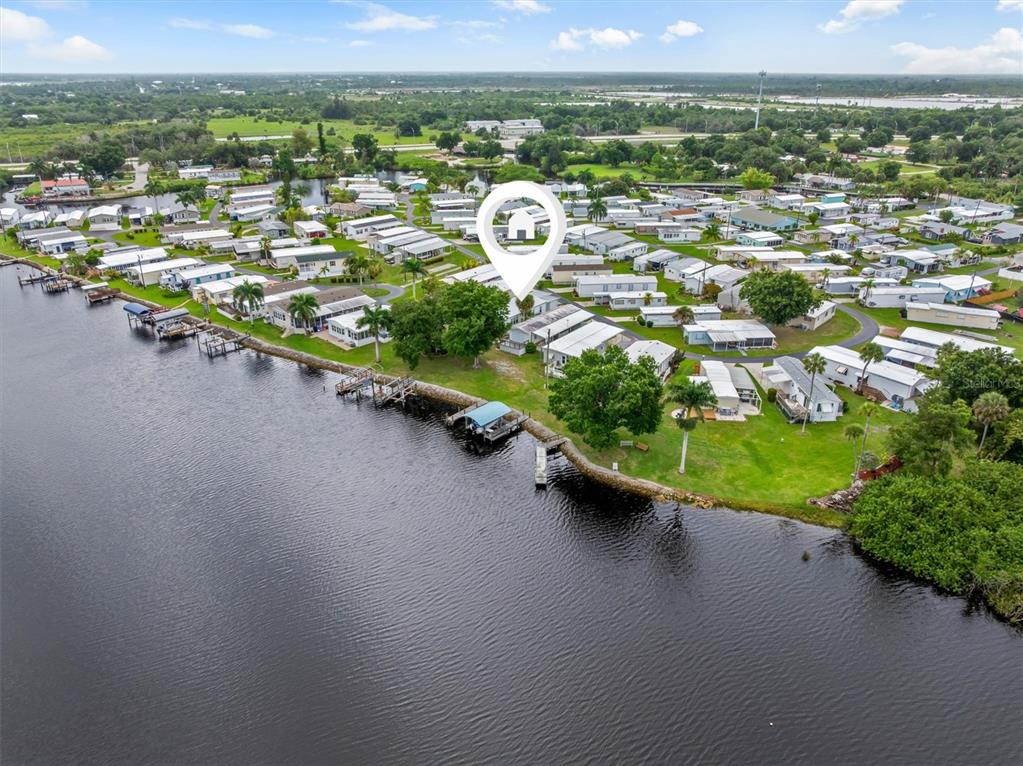 An aerial view shows a waterfront mobile home community with a highlighted residence — 8320 RIVERSIDE DRIVE UNIT 99, PUNTA GORDA, FL