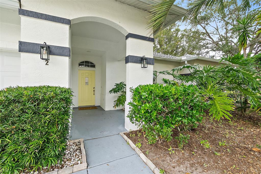The exterior of a house features a yellow front door, a covered entryway, and landscaping — 2 SAW MILL COURT, PALM COAST, FL