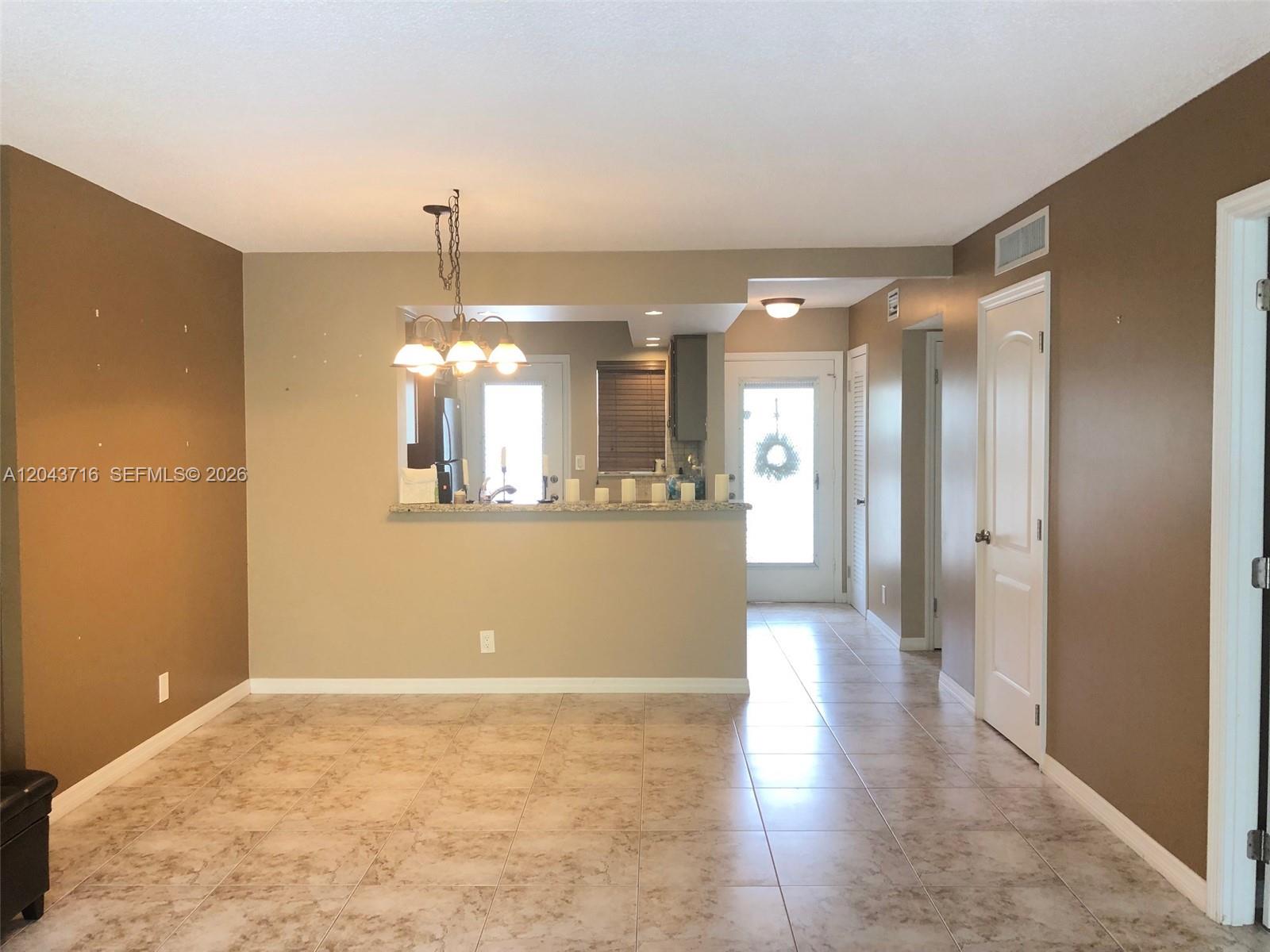 A dining area with tile flooring features a pass-through window looking into the kitchen — 320 NE 12th Ave # 303, Hallandale Beach FL 33009, HALLANDALE BEACH, FL