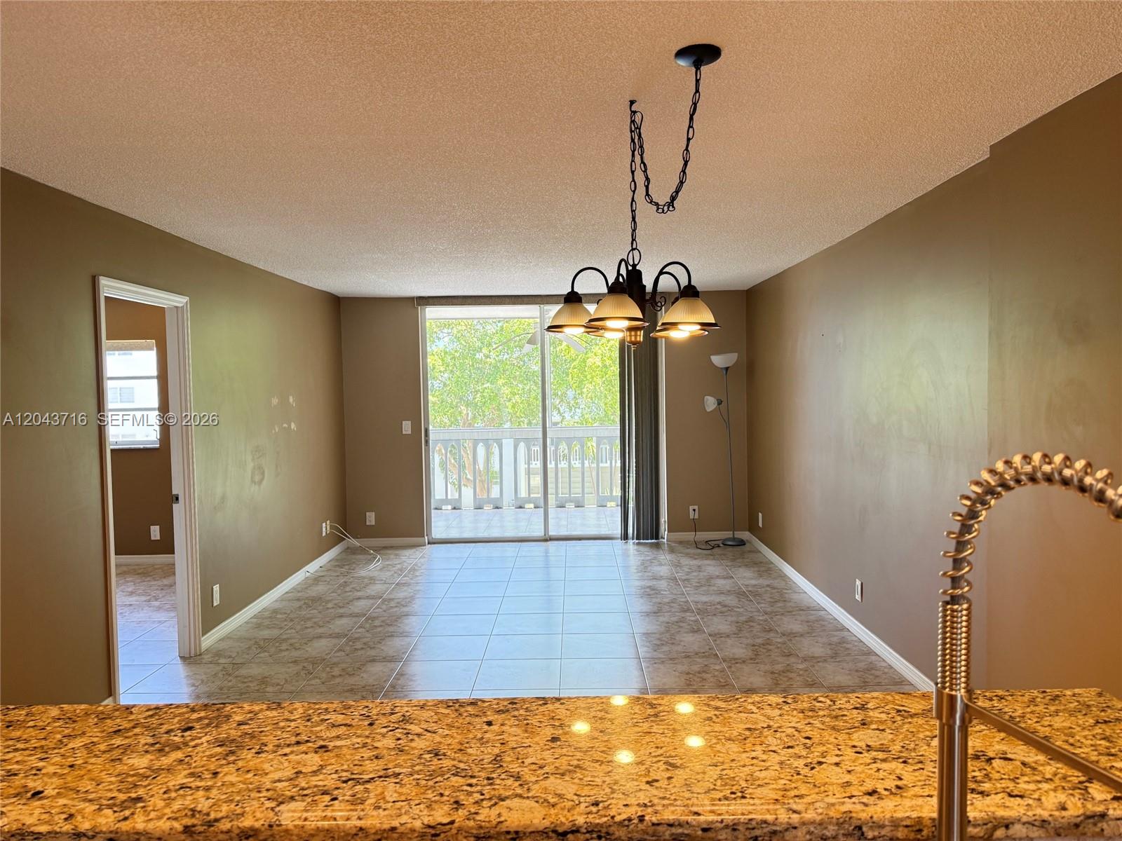 A dining area with tile floors, a chandelier, and a sliding door to a balcony — 320 NE 12th Ave # 303, Hallandale Beach FL 33009, HALLANDALE BEACH, FL
