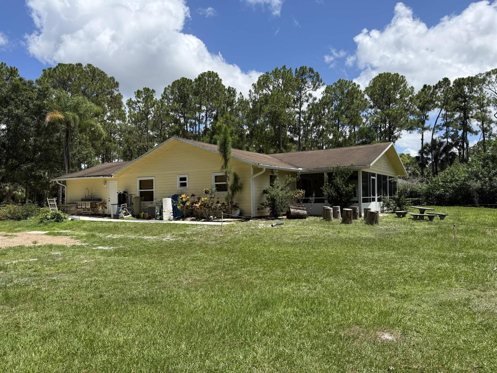 A yellow single-story house with a screened-in porch sits on a large grassy lot — 15647 N 116th Ter Terrace N, FL 33478, FL