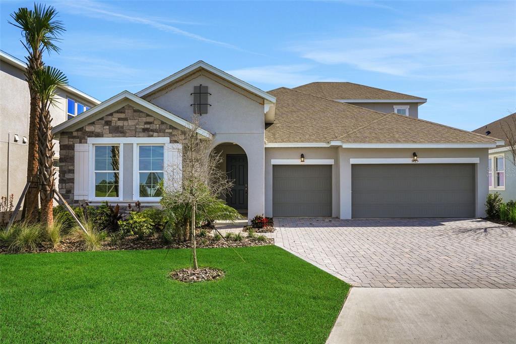 A single-story suburban house with a stone facade, two-car garage, and a paved driveway — 7425 SEA MANATEE STREET, PARRISH, FL