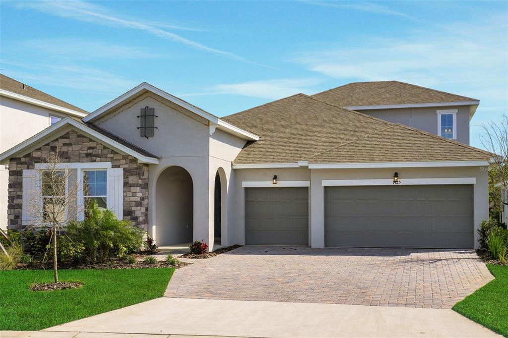A single-story house with a stone facade, arched entryway, and a three-car garage — 7425 SEA MANATEE STREET, PARRISH, FL