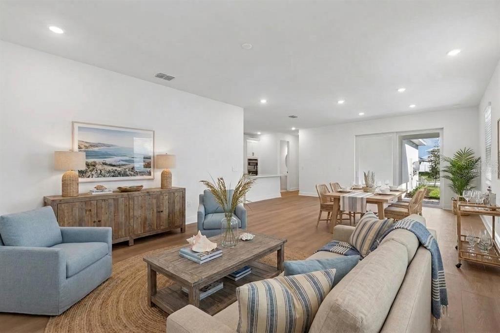 A living and dining area with light wood floors, blue armchairs, and a wooden console — 8103 SEAFLOWER PARKWAY, BRADENTON, FL