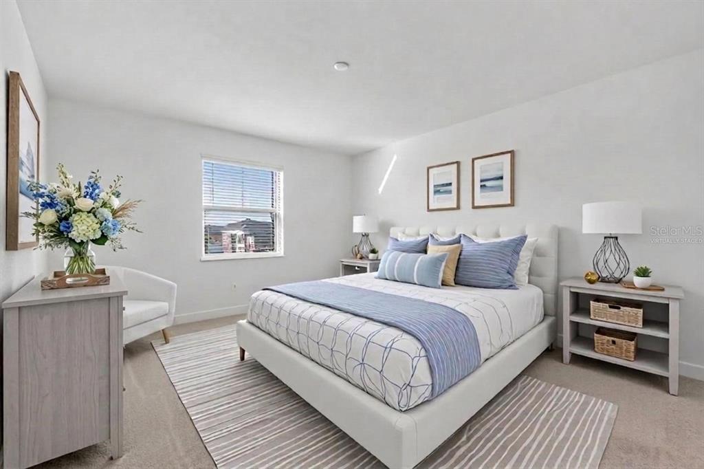 A bedroom with a bed, nightstands, a dresser, a chair, and a rug on carpet — 8103 SEAFLOWER PARKWAY, BRADENTON, FL