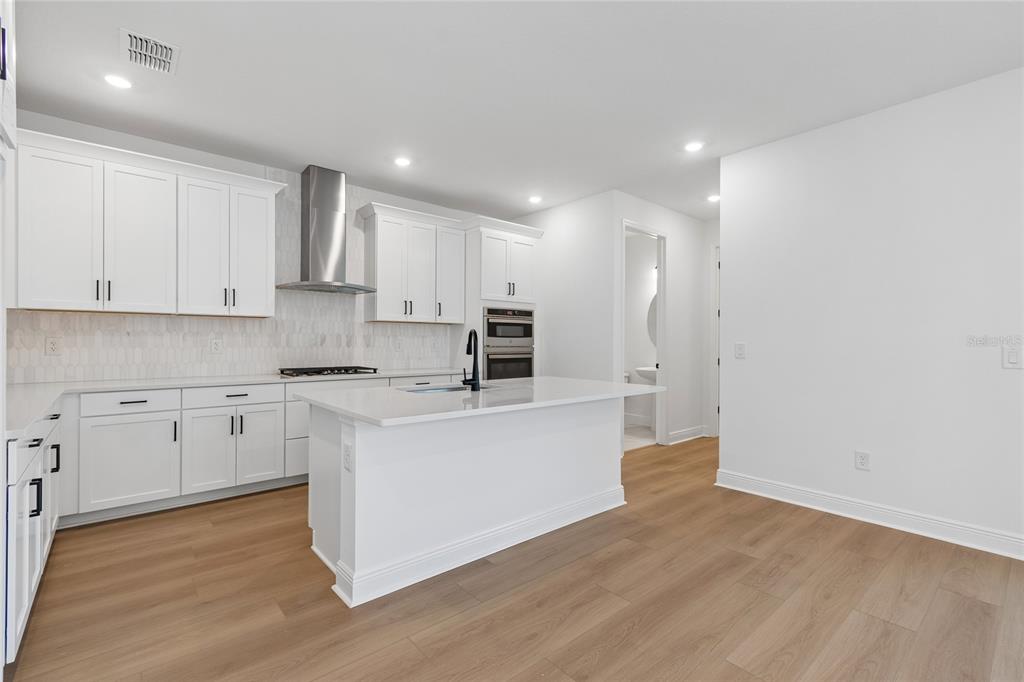 A modern kitchen with white cabinets, a central island, and light wood flooring — 8103 SEAFLOWER PARKWAY, BRADENTON, FL