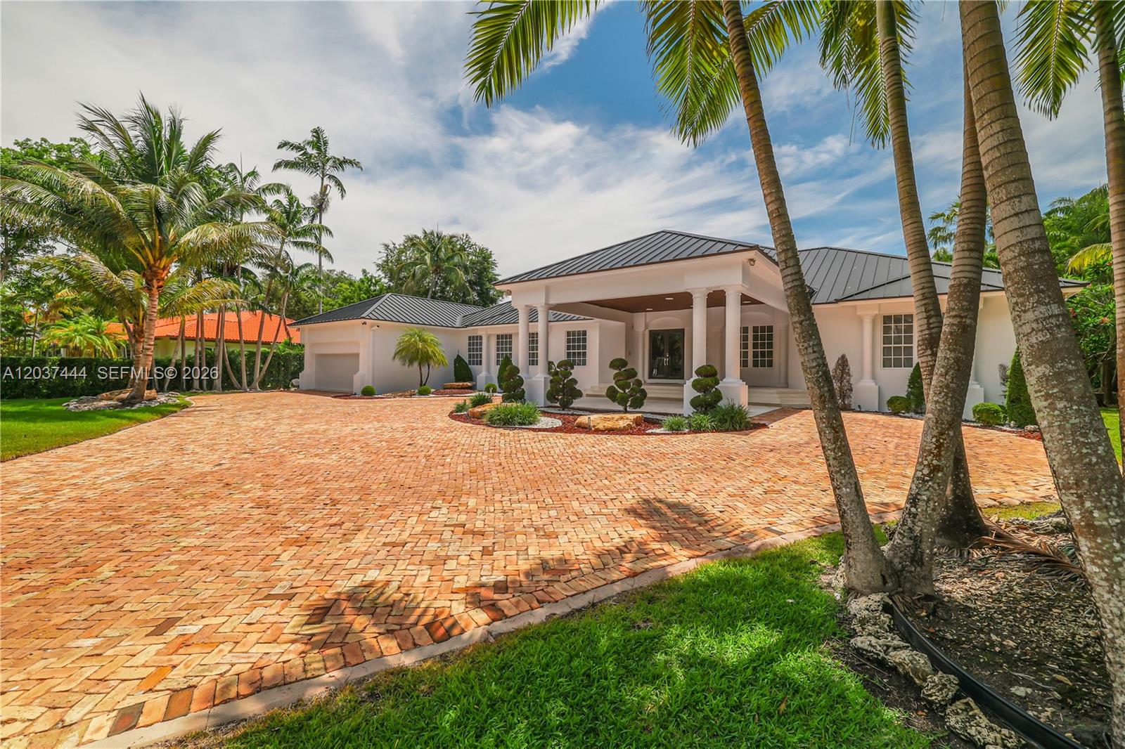 A white single-story house with a metal roof and a large brick-paved driveway — 12201 SW 92nd Ave, Miami FL 33176, MIAMI, FL