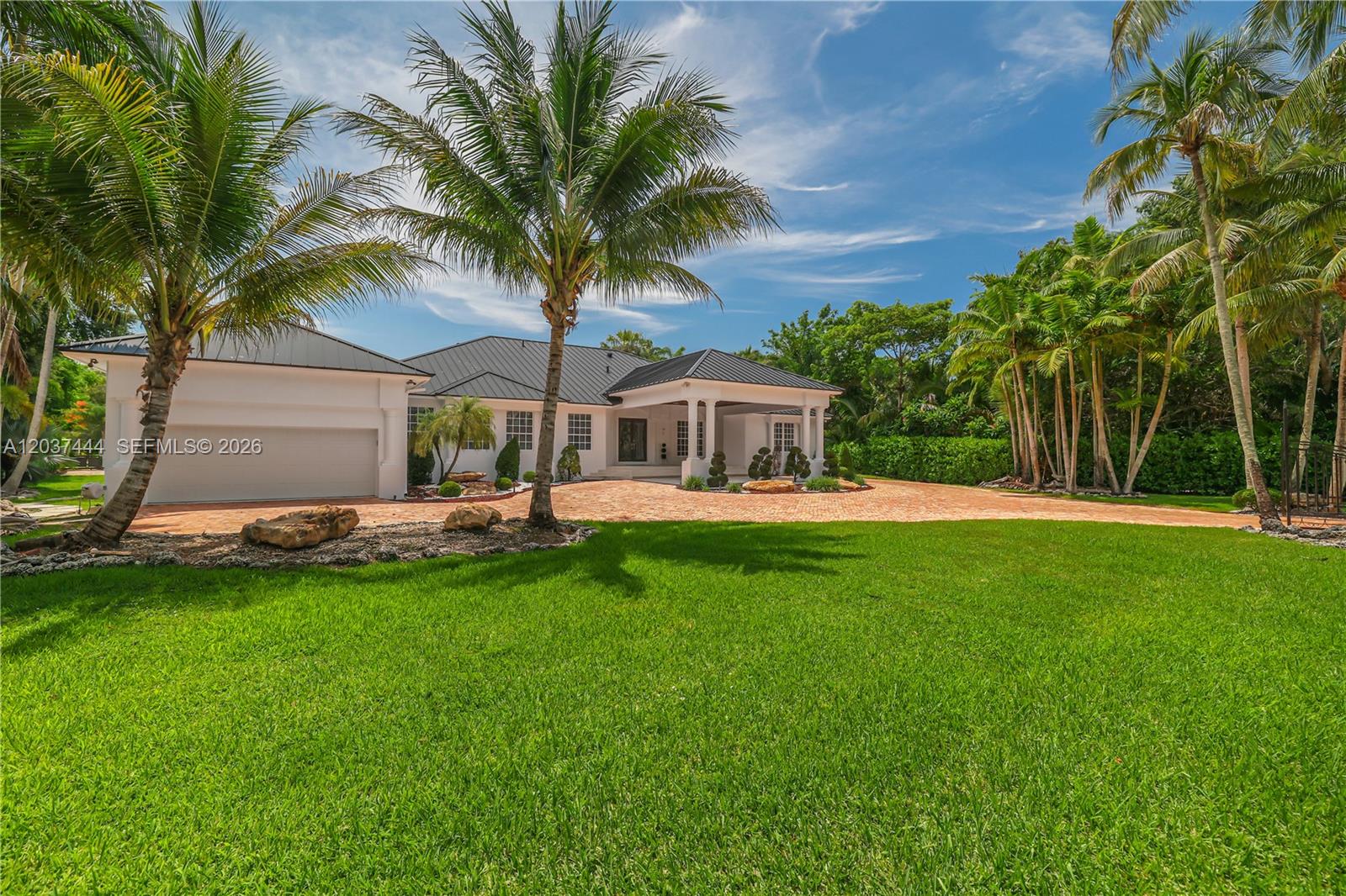 A white single-story house with a dark metal roof and a brick driveway — 12201 SW 92nd Ave, Miami FL 33176, MIAMI, FL