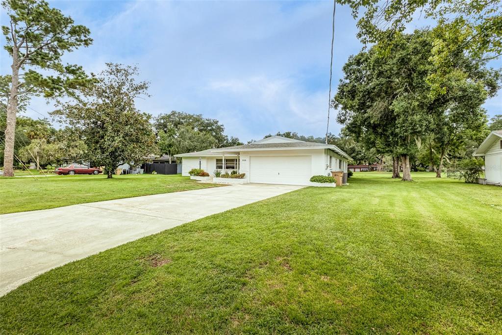 A white, single-story ranch-style house features a large front lawn and a concrete driveway — 936 N RIVERHILLS DRIVE, TAMPA, FL