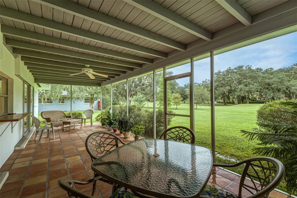 A screened-in patio with a tiled floor, dining set, and views of a grassy yard — 936 N RIVERHILLS DRIVE, TAMPA, FL