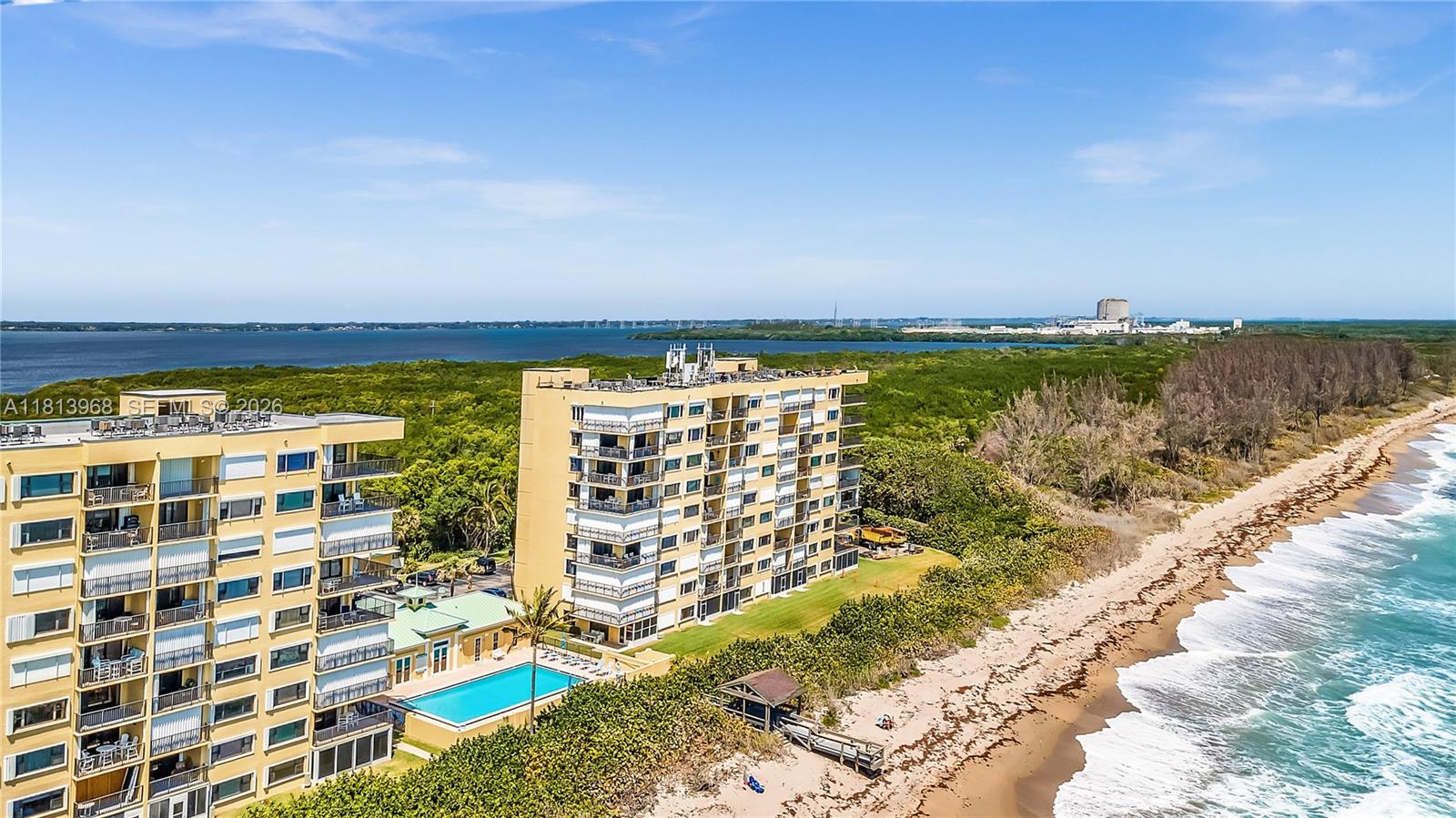 An aerial view shows two beachfront apartment buildings with a pool next to the ocean — 7370 S Ocean Dr # 815, Jensen Beach FL 34957, JENSEN BEACH, FL