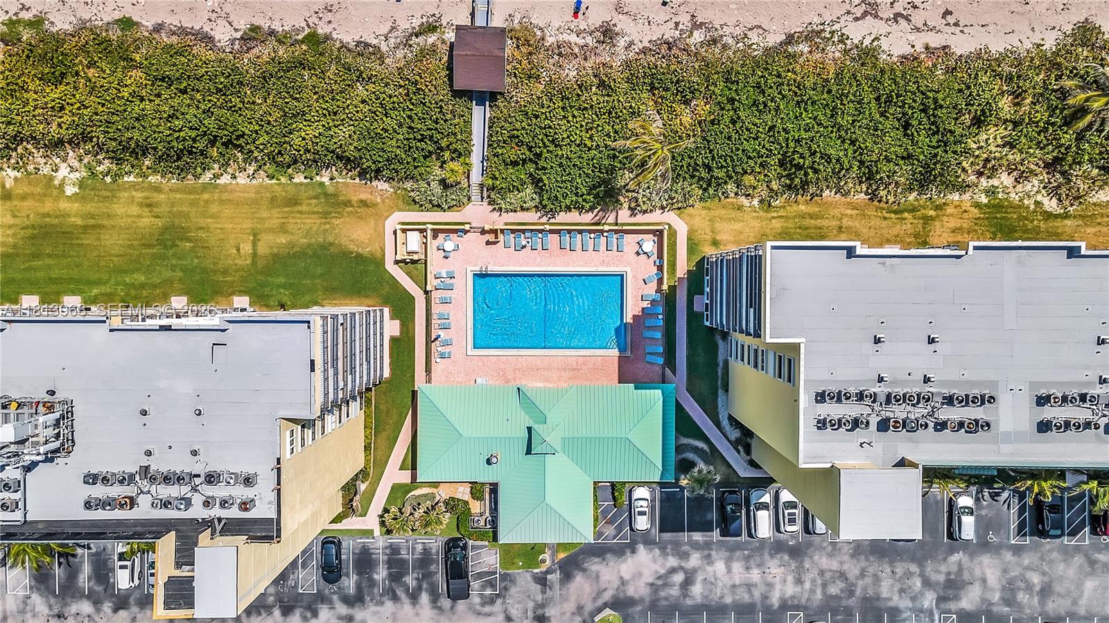 An aerial view shows a swimming pool between two apartment buildings with a beach walkway — 7370 S Ocean Dr # 815, Jensen Beach FL 34957, JENSEN BEACH, FL