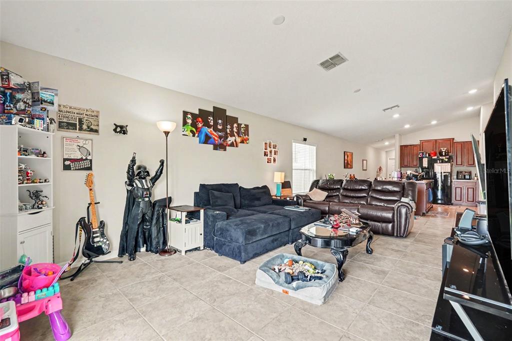 A living room features tile flooring, a dark sectional sofa, a leather couch, and pop-culture decor — 17054 YELLOW PINE STREET, WIMAUMA, FL
