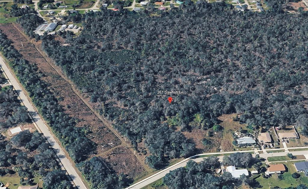 An aerial view shows a densely wooded, undeveloped rectangular lot surrounded by residential streets — 261 SAWFISH LANE, PUNTA GORDA, FL
