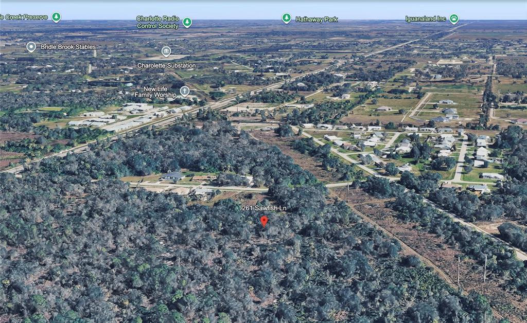 An aerial view of a wooded lot with a red location marker — 261 SAWFISH LANE, PUNTA GORDA, FL