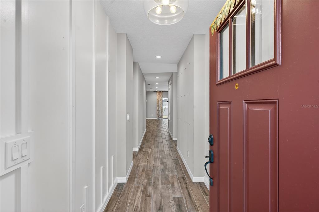 A view from an open front door into a hallway with wood-look tile flooring — 1245 CELERY OAKS LANE, SANFORD, FL