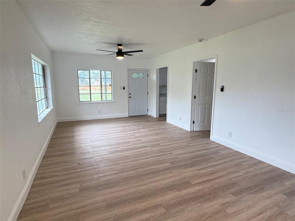 An empty room features white walls, light wood-look flooring, a ceiling fan, and two windows — 165 E POMELO STREET, GROVELAND, FL