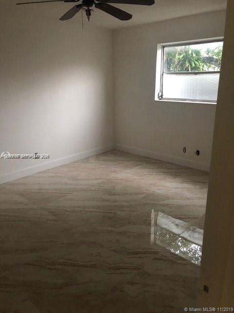 An empty bedroom features white walls, a ceiling fan, and glossy, light-colored marble-style flooring — 1715 Wiley St # 5, Hollywood FL 33020, HOLLYWOOD, FL