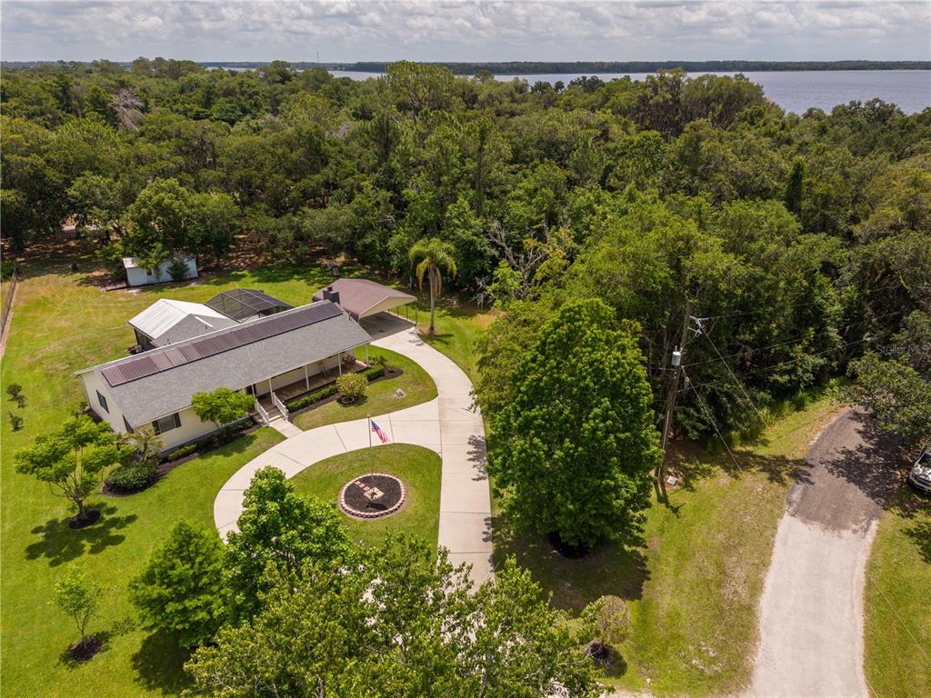 An aerial view shows a house with a metal roof, carport, and circular driveway — 2955 GODWIN ROAD, ST CLOUD, FL