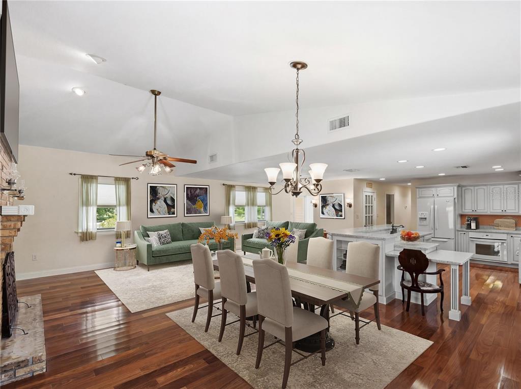 An open-concept living and dining area features hardwood floors, a vaulted ceiling, and white cabinetry — 2955 GODWIN ROAD, ST CLOUD, FL