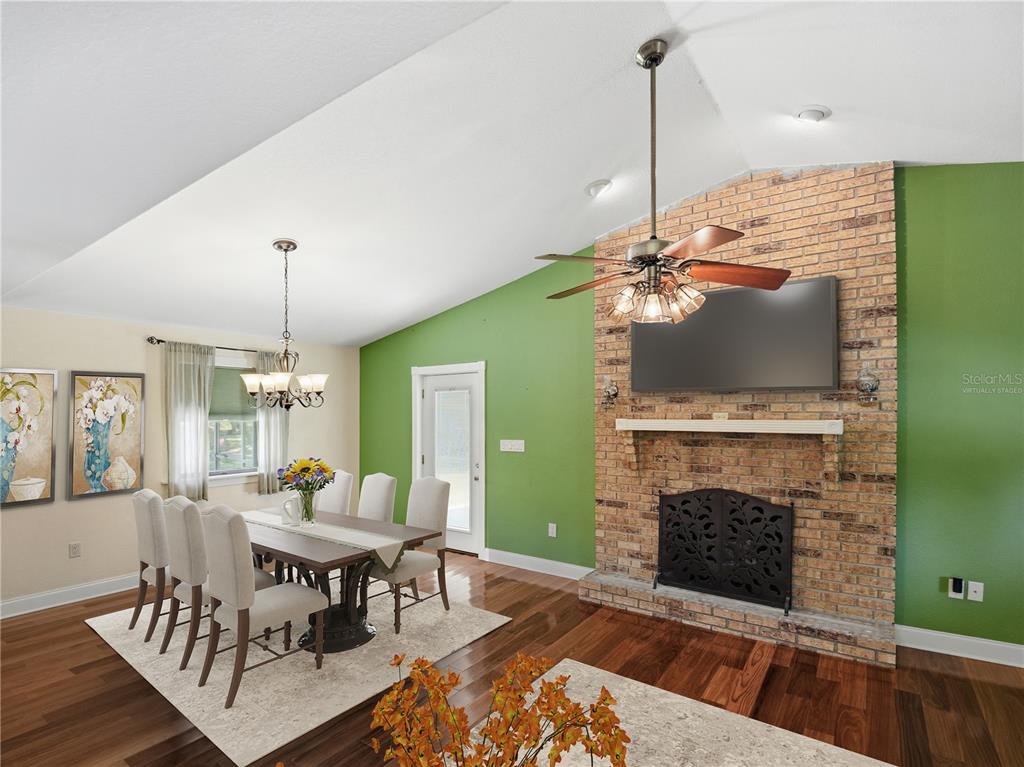A dining area with a brick fireplace and green walls features a vaulted ceiling — 2955 GODWIN ROAD, ST CLOUD, FL