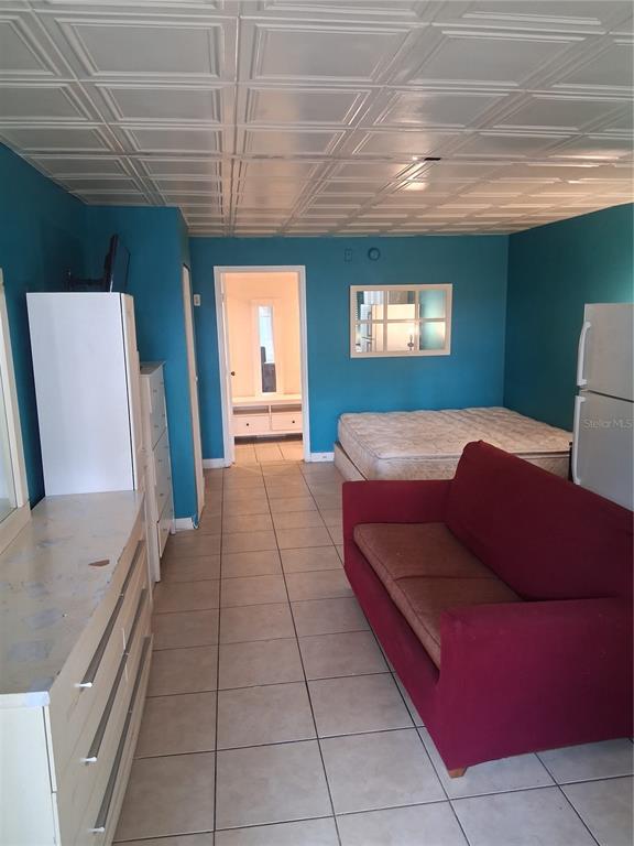 A room with blue walls, a tiled ceiling, a red sofa, and a mattress — 8421 S ORANGE BLOSSOM TRAIL UNIT 339, ORLANDO, FL
