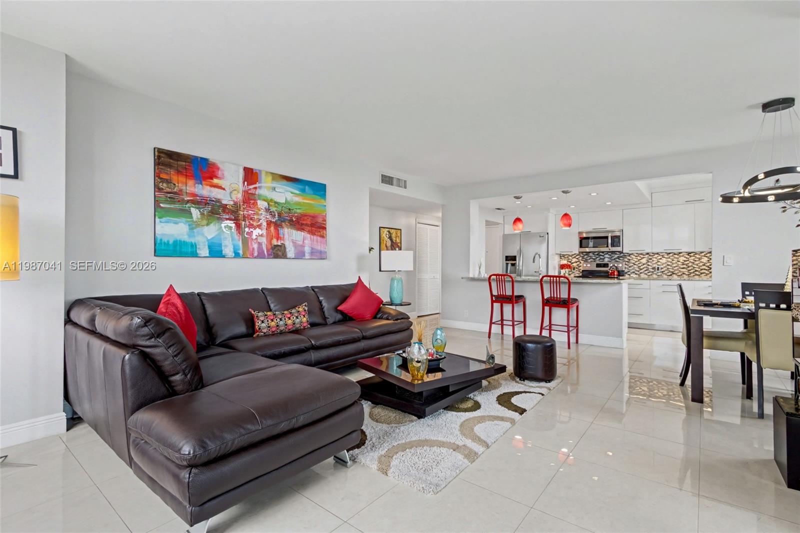 A living room with a dark leather sectional, coffee table, and an open-concept kitchen — 4330 Hillcrest Dr # 619, Hollywood FL 33021, HOLLYWOOD, FL