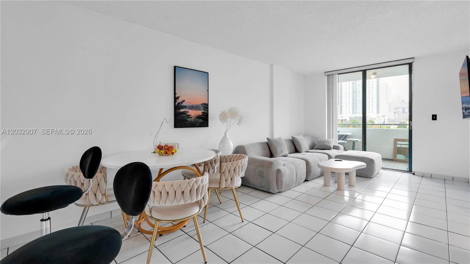 A living and dining area features white tile floors, a grey sectional, and a balcony — 546 SW 1st St # 603, Miami FL 33130, MIAMI, FL