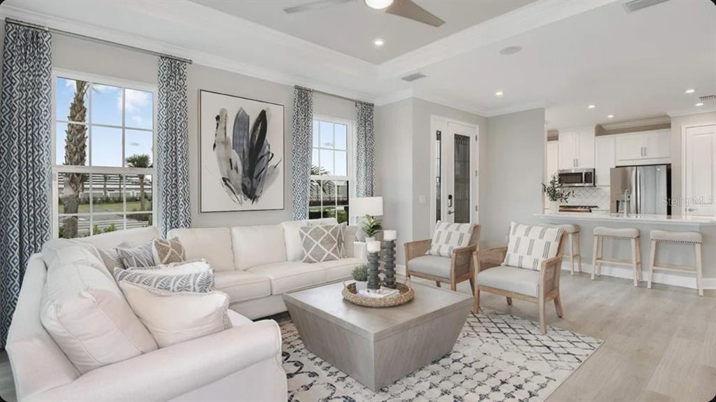 A living room with a white sofa, two armchairs, a coffee table, and an open kitchen — 7536 MOONBEAM AVENUE, SARASOTA, FL