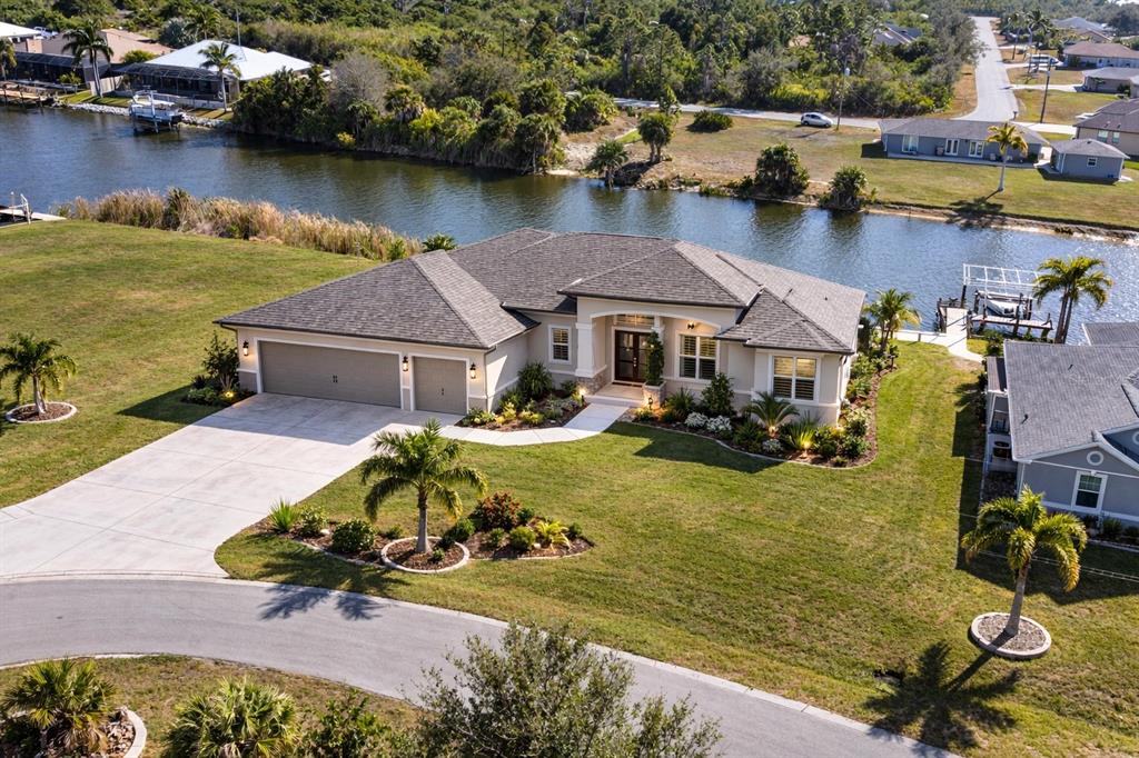 An aerial view of a single-story house with a three-car garage and a canal — 9548 ATTICA CIRCLE, PORT CHARLOTTE, FL