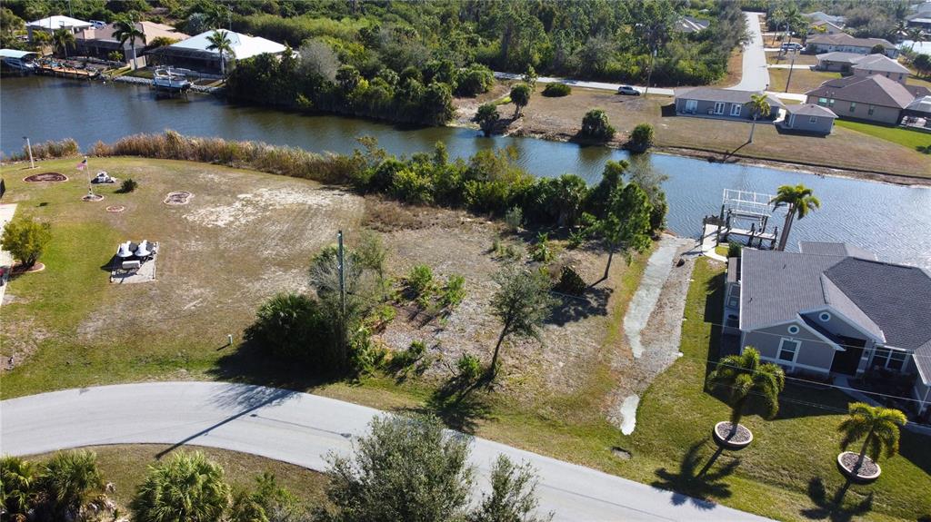 An aerial view shows a vacant waterfront lot situated between two residential properties — 9548 ATTICA CIRCLE, PORT CHARLOTTE, FL