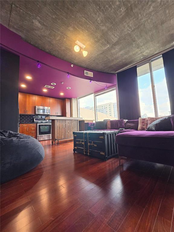 A living room and kitchen area features purple walls, a concrete ceiling, and hardwood floors — 155 S COURT AVENUE UNIT 1009, ORLANDO, FL