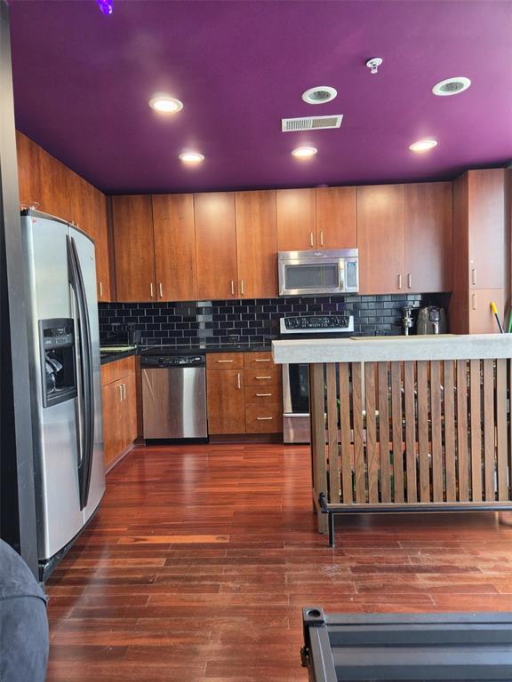 A kitchen features wood cabinets, stainless steel appliances, a black subway tile backsplash, and purple ceiling — 155 S COURT AVENUE UNIT 1009, ORLANDO, FL
