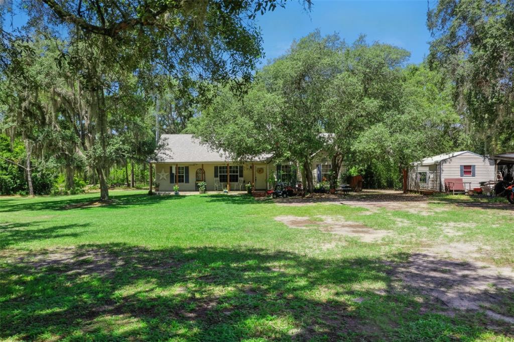 A single-story house with a covered porch sits on a large, tree-shaded grassy lot — 5500 VENTURA ACRES ROAD, GROVELAND, FL