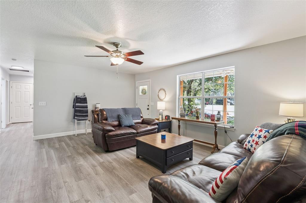 A living room features two brown leather sofas, a coffee table, and wood-look flooring — 5500 VENTURA ACRES ROAD, GROVELAND, FL