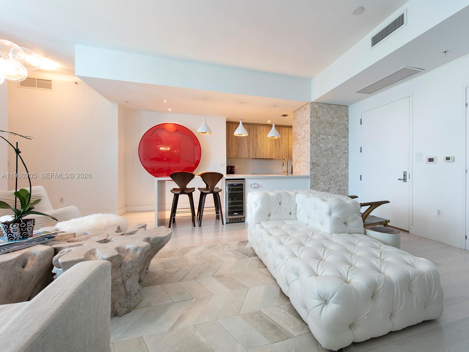 A modern open-concept living room features a white tufted sofa, a wooden coffee table, and a kitchen — 50 S Pointe Dr # 707, Miami Beach FL 33139, MIAMI BEACH, FL