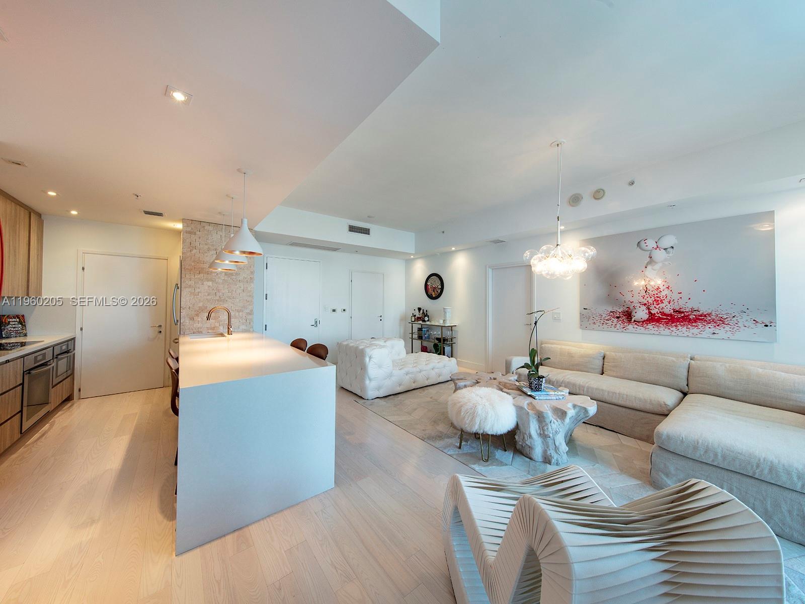 A modern open-concept living room features a kitchen island, light wood floors, and neutral furniture — 50 S Pointe Dr # 707, Miami Beach FL 33139, MIAMI BEACH, FL