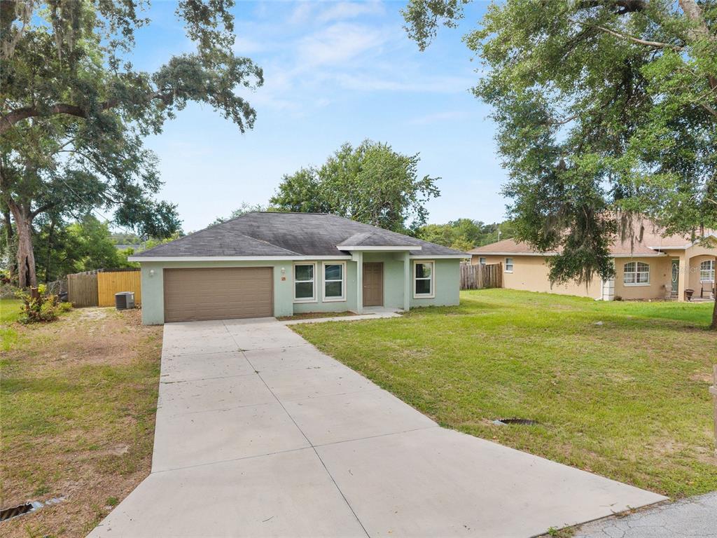 A single-story light green house with a two-car garage and a concrete driveway — 25 DOGWOOD DRIVE TRAIL, OCALA, FL