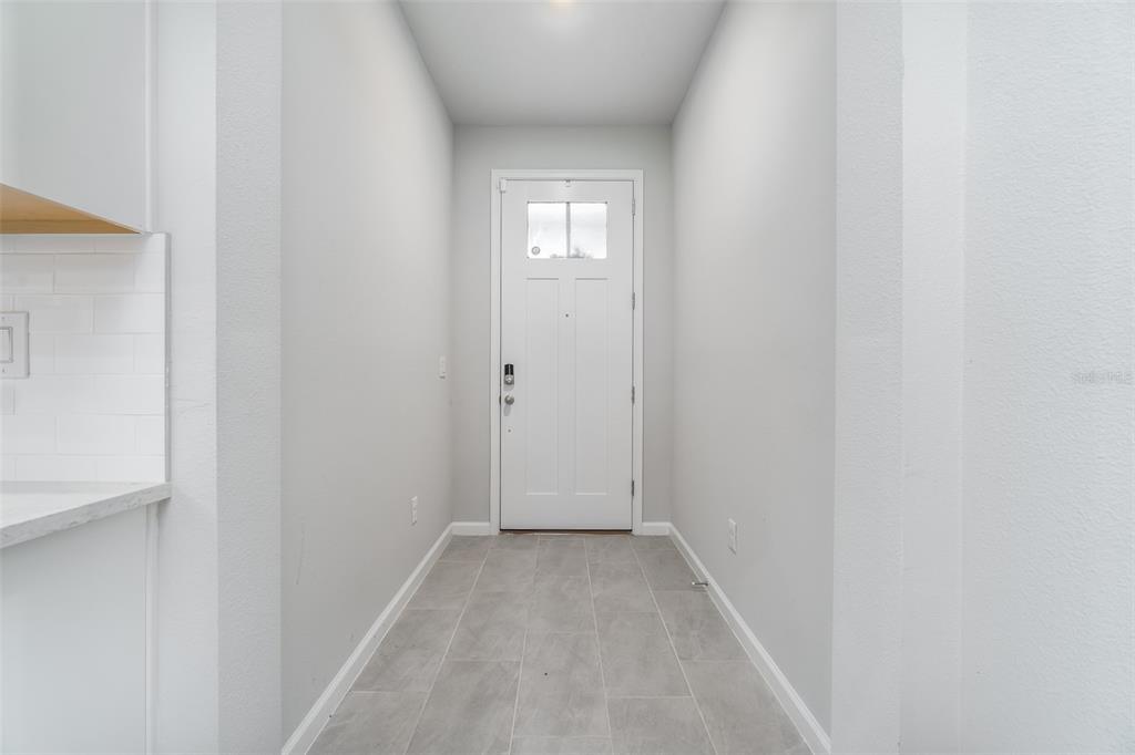 A narrow entryway features light gray walls, tiled flooring, and a white front door — 8518 PRIMROSE WILLOW PLACE, ODESSA, FL