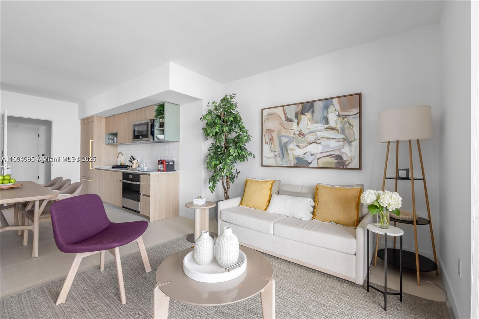 A modern living room features a beige sofa, a purple chair, and an open kitchen — 159 NE 6TH ST # 2916, Miami FL 33132, MIAMI, FL