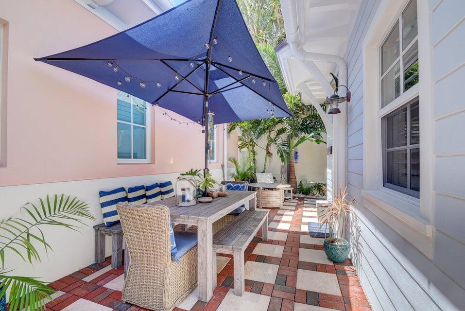 A patio features a wooden dining table, benches, a wicker chair, and a blue umbrella — 2225 S Ocean Boulevard # a, Delray Beach FL 33483, DELRAY BEACH, FL