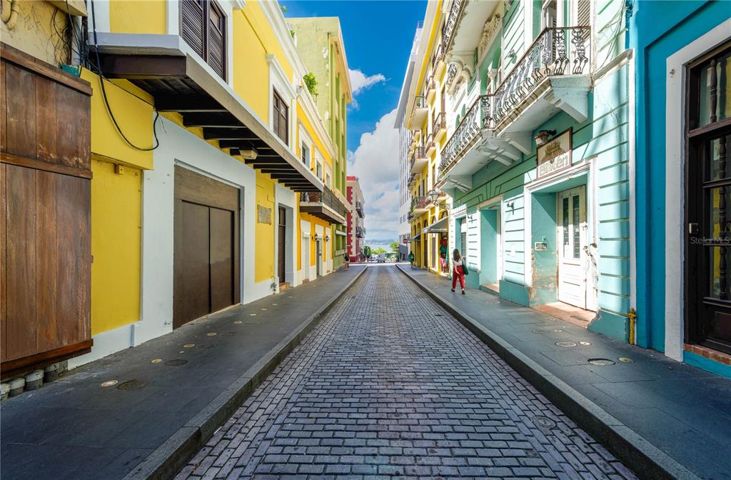 A narrow cobblestone street is lined with colorful yellow and turquoise historic buildings — 255 SAN JUSTO STREET, SAN JUAN, PR