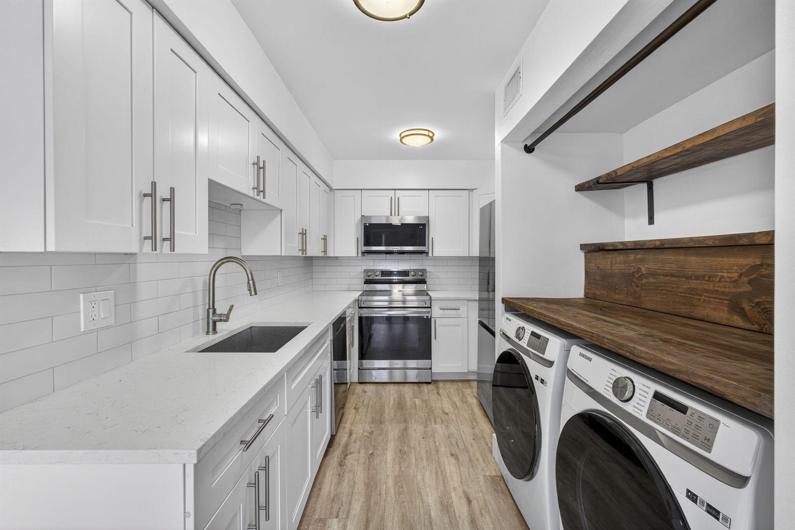 A modern kitchen features white cabinets, stainless steel appliances, quartz countertops, and an integrated laundry area — 9746 Nickels Boulevard # 103, Boynton Beach FL 33436, BOYNTON BEACH, FL