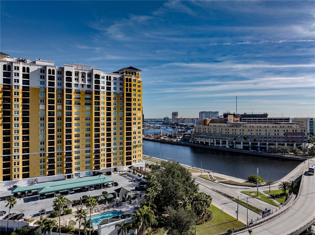 An aerial view shows a tall yellow apartment building beside a river and bridge — 345 BAYSHORE BOULEVARD UNIT 1203, TAMPA, FL