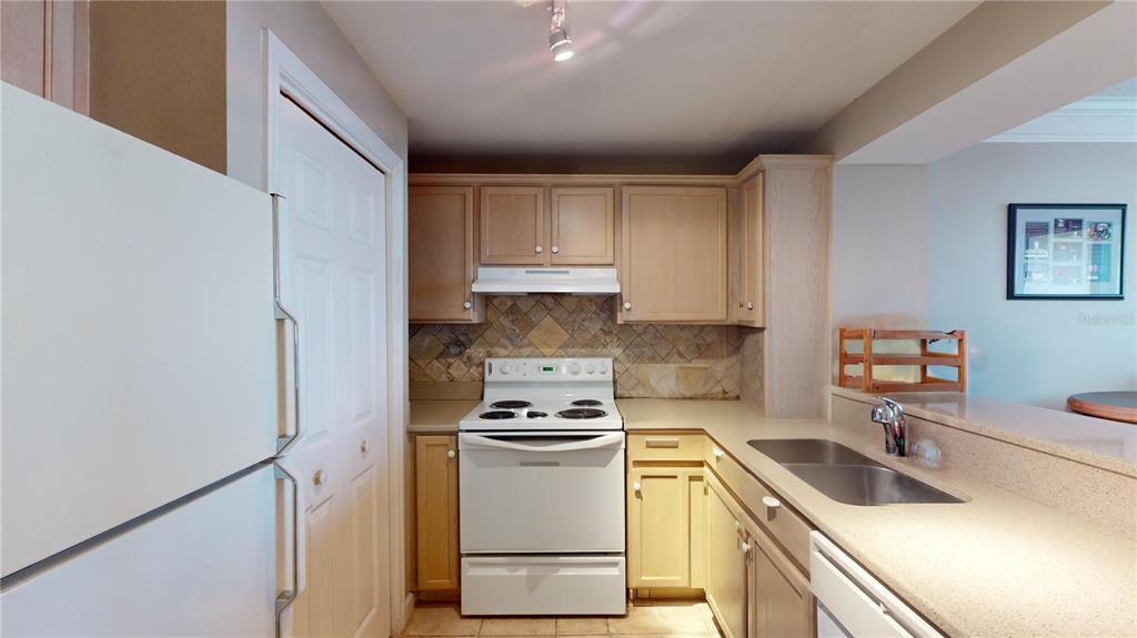 A kitchen features light wood cabinets, white appliances, a tiled backsplash, and a double sink — 345 BAYSHORE BOULEVARD UNIT 1203, TAMPA, FL
