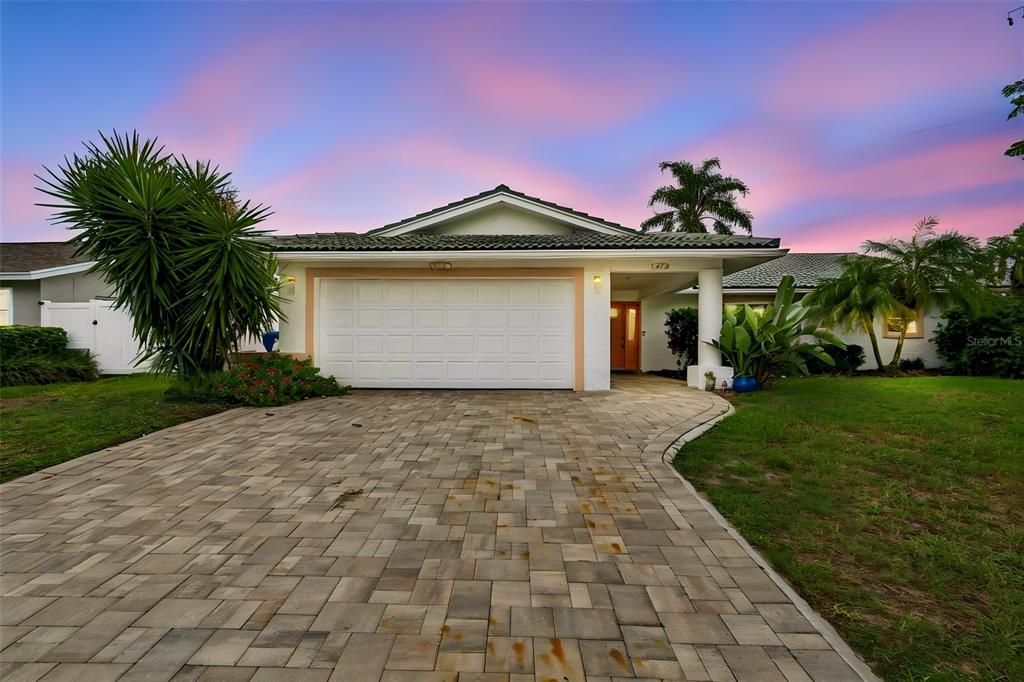 A single-story house with a white garage door and a paved driveway at sunset — 1473 50TH AVENUE NE, ST PETERSBURG, FL