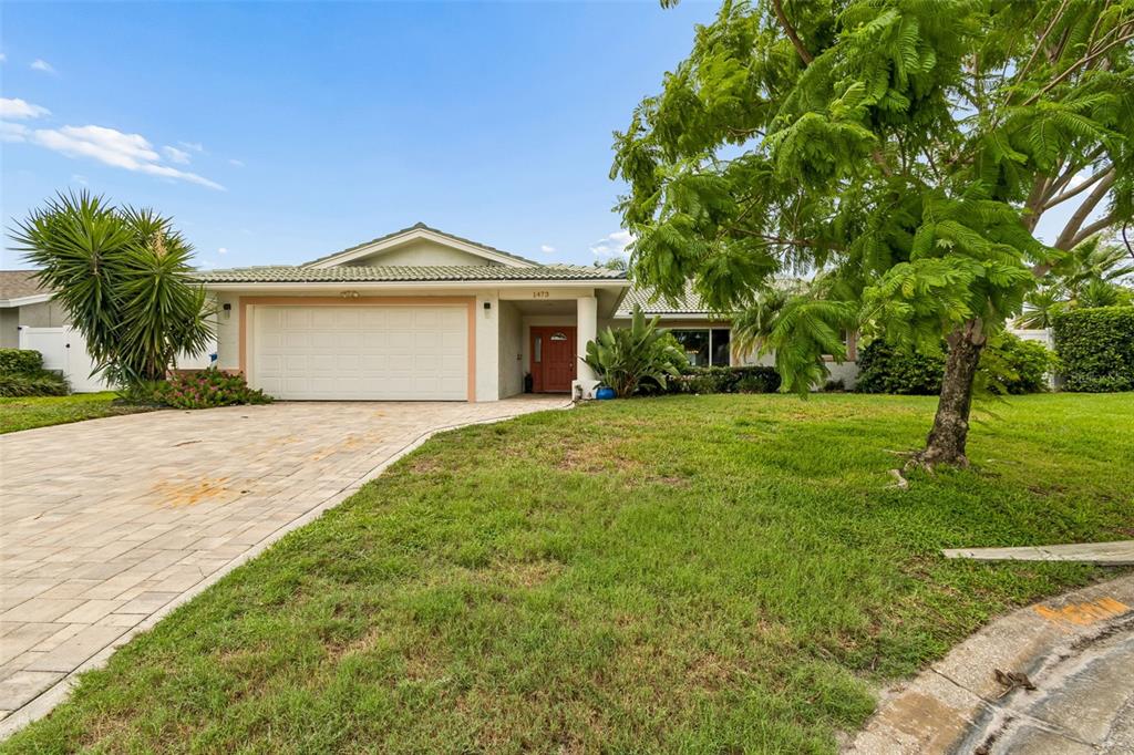 A single-story house with a paved driveway, a two-car garage, and a large front tree — 1473 50TH AVENUE NE, ST PETERSBURG, FL